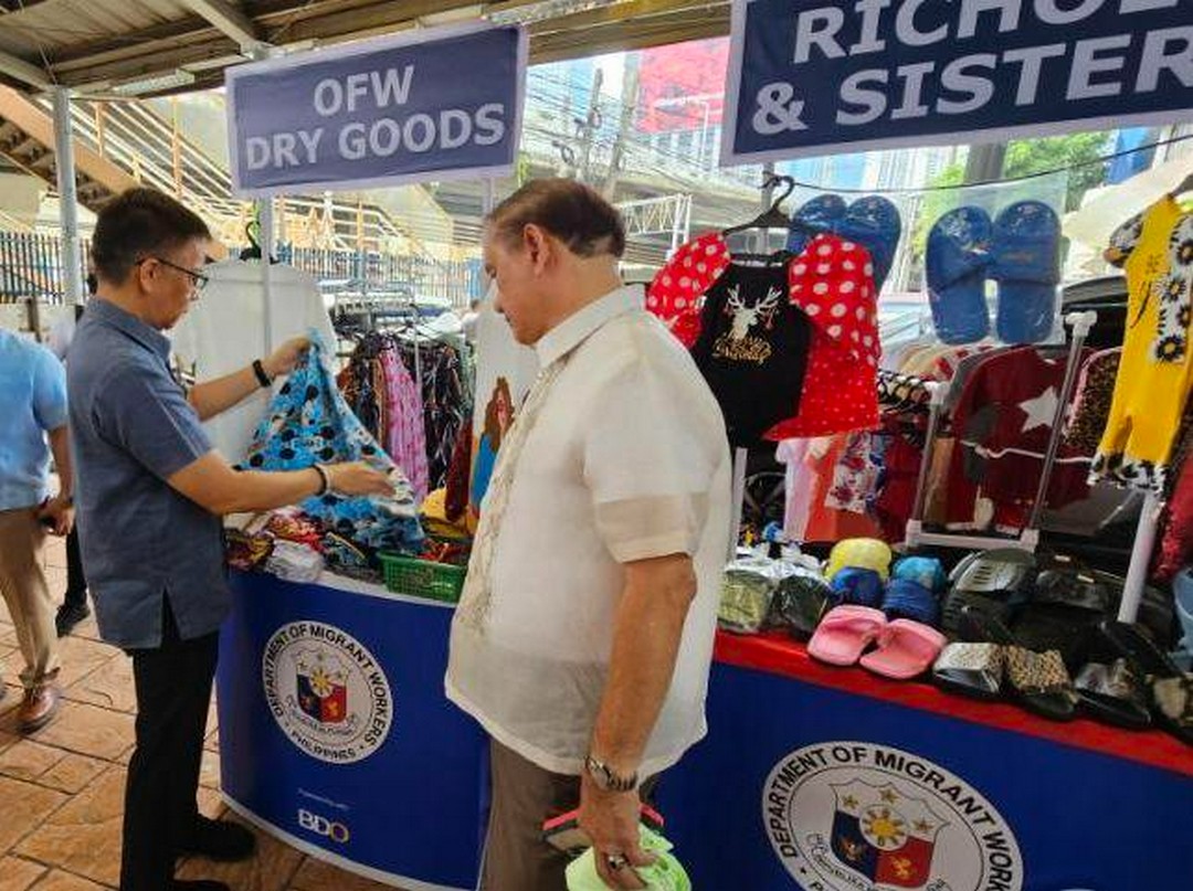 Open for business. DMW Sec. Cacdac (left) and former Labor Secretary Marianito Roque check on some garments for sale during the launch of the BalikKabayan Bazaar.